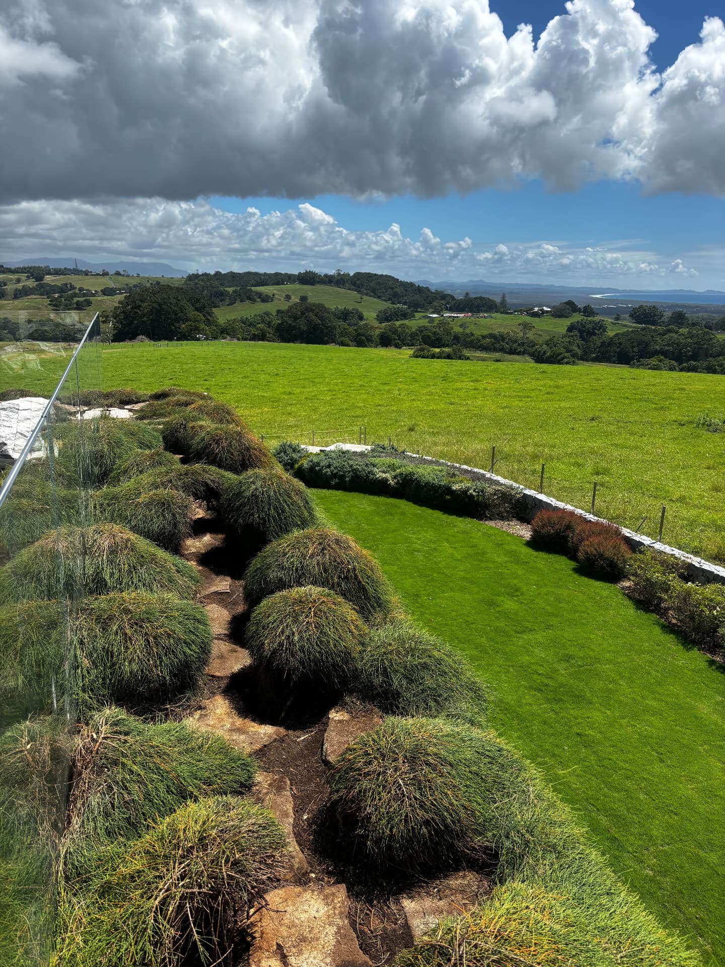 Garden of sculpted shrubs overlooking green hills and the coast
